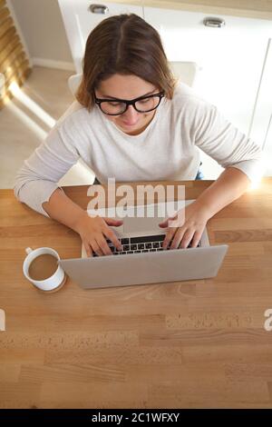 Top view of womans hands typing on laptop keypad wearing glasses and coffee on the table Stock Photo