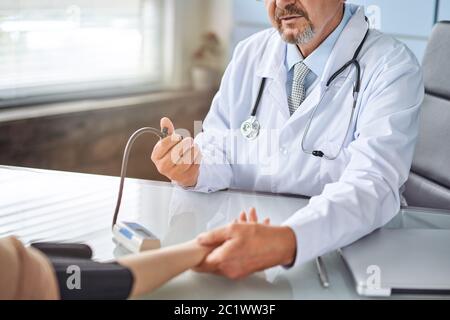 Young woman at the doctor appointment. The doctor measures the pressure of the patient Stock Photo