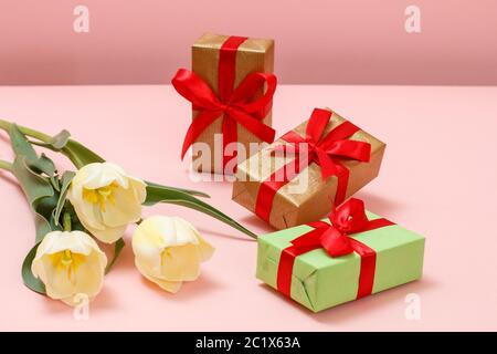 Gift boxes with beautiful yellow tulips on a pink background. Concept of giving a gift on holidays. Stock Photo