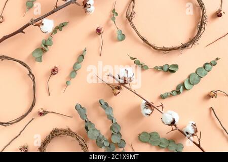 Pattern made of wreath blanks, dried eucalyptus, roses, cotton branches on yellow background Stock Photo