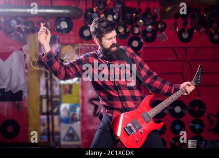 Man with shouting face play guitar, singing song, play music, music club background. Frontman concept. Musician full of energy, soloist, singer. Musician with beard play electric guitar. Stock Photo