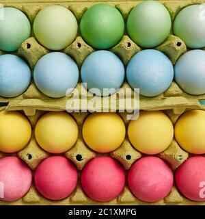 Different colored painted Easter eggs in yellow cardboard boxes. Creative Easter pattern as layout. Flat lay Stock Photo
