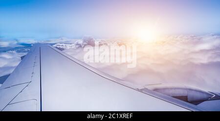 Wing of airplane above the clouds at sunrise. Stock Photo