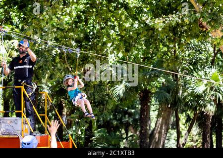 Emergency Unit instructor assisting kid in zip line during display of Spanish Armed Forces Day in Seville, Spain. Stock Photo