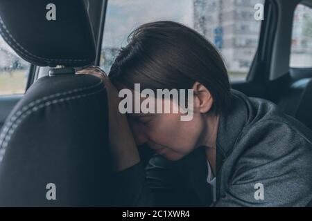Tired businesswoman sleeping at car back seat, exhausted female executive fallen asleep in corporate limousine Stock Photo
