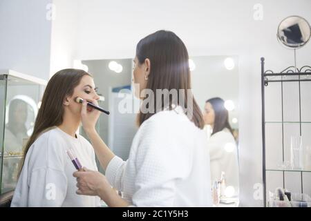 Professional make up artist doing make up in beauty salon Stock Photo