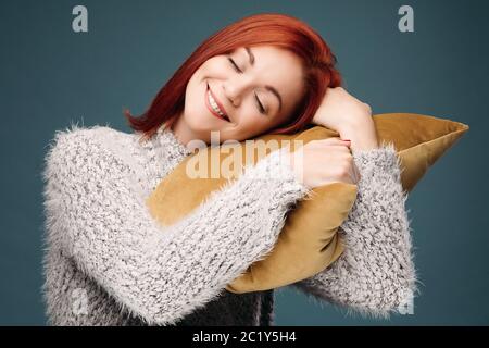 Studio portrait of a woman in a sweater hugging a pillow. Stock Photo