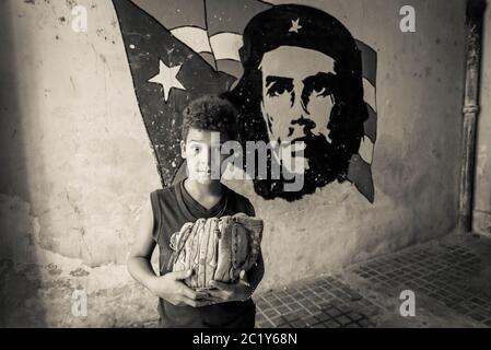 Boy next to Che Guevara wall painting , Old City Centre, Havana Vieja, Havana, Cuba Stock Photo