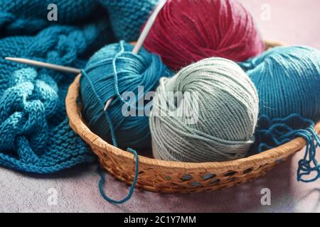 balls of colored yarn with spokes in a wicker basket close-up Stock Photo