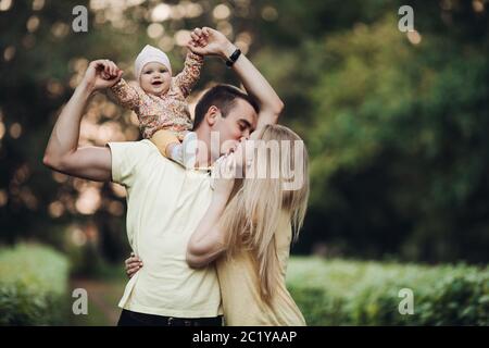 Portrait of lovely young family sitting together outside. Stock Photo