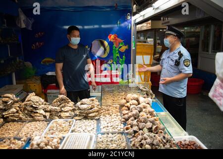 (200616) -- BEIJING, June 16, 2020 (Xinhua) -- A staff member from the market supervision administration of Fengtai District inspects the sea food trading hall of the Yuegezhuang wholesale market in Beijing, capital of China, June 16, 2020. Beijing has disinfected 276 farm produce markets and closed 11 such underground and semi-underground markets as of 6 a.m. Tuesday to better curb the spread of the novel coronavirus, Chen Yankai, deputy director of the municipal market supervision bureau, told a press conference on Tuesday. A total of 33,173 catering service providers have also been disin Stock Photo