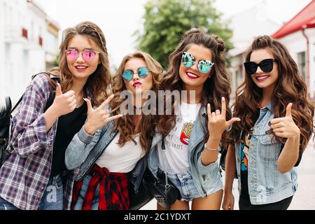 Tredny smiling girlfriends walking along the street with the only man. Stock Photo