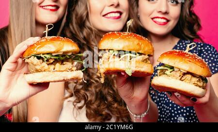 crop of friends holding yummy hamburgers with chicken and vegetables. Stock Photo