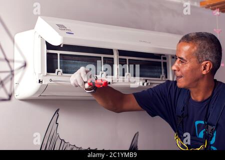 Man worker fixing air conditioning on the wall. Professional service Stock Photo