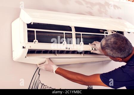 Man worker fixing air conditioning on the wall. Professional service Stock Photo