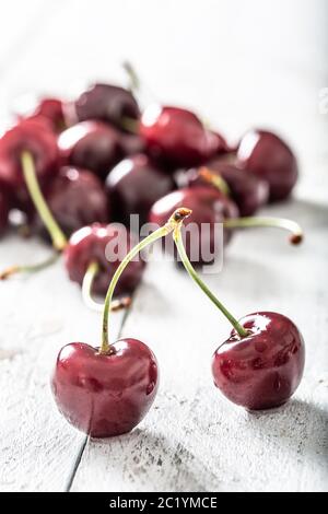 Twin cherries on a wooden table and a bunch of fresh cherries in the background Stock Photo