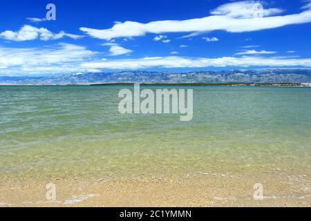 Sandy beach in Nin, Croatia. Velebit mountain, blue sky and white clouds in background. Stock Photo
