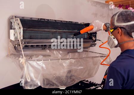 Man worker doing professional cleaning of air conditioning. Stock Photo
