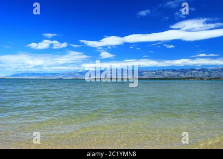 Sandy beach in Nin, Croatia. Velebit mountain, blue sky and white clouds in background. Stock Photo
