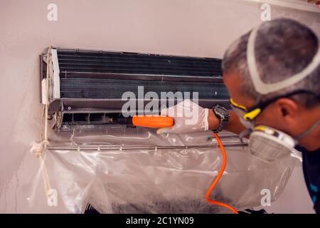 Man worker doing professional cleaning of air conditioning. Stock Photo