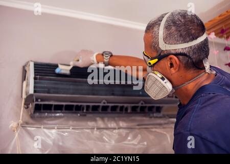Man worker doing professional cleaning of air conditioning. Stock Photo