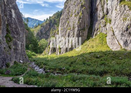 a small stream flows between the mountains and flows into the river Stock Photo