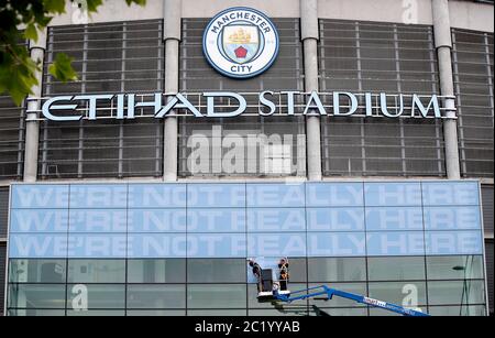 Workmen place signs at main entrance to the Etihad Stadium, home of Manchester City. The Premier League restarts tomorrow night with Aston Villa v Sheffield United and Manchester City v Arsenal. Stock Photo