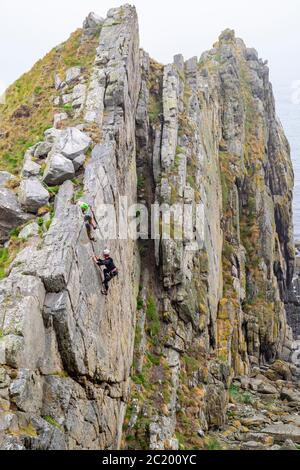 CULLEN TOWN MORAY COAST SCOTLAND TWO CLIMBERS ON A ROCK FACE USED FOR PRACTICE BY ROCK CLIMBERS Stock Photo