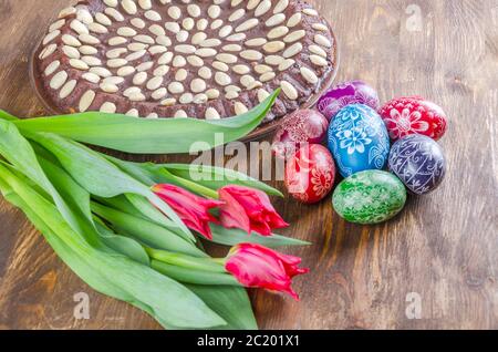 colorful easter eggs, easter cake and tulips on wooden table Stock Photo