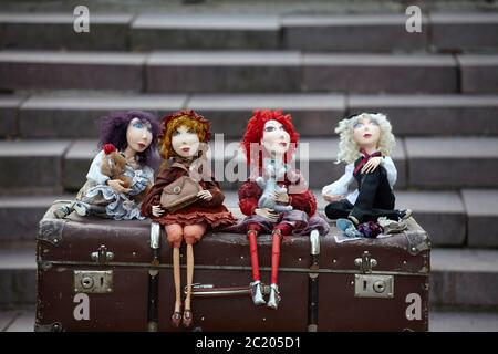 Druskininkai, Lithuania - August 11, 2017: Handmade dolls sit on an old vintage suitcase at local sunday fair. Stock Photo