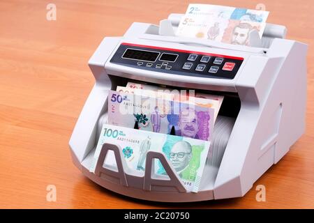 Colombian Pesos in a counting machine Stock Photo