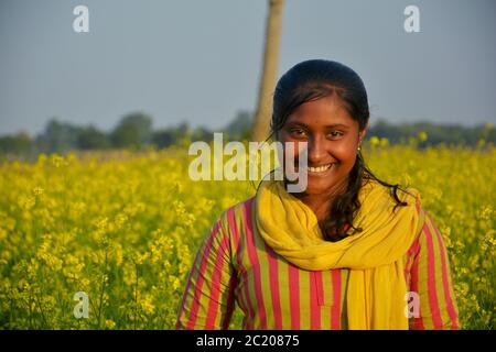 : An Indian teenage girls smiling and posing for photograph in a mustard field, selective focusing Stock Photo