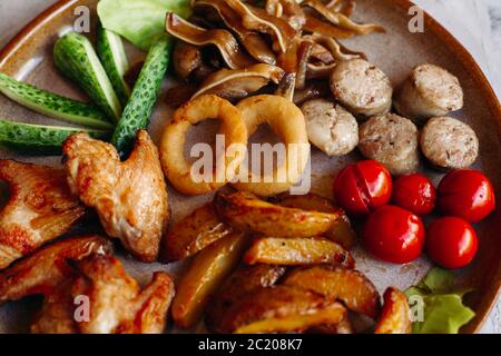 Clay plate full of delicious appetizers standing on white surface. Stock Photo