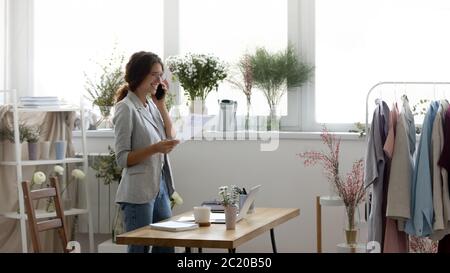 Young female fashion designer talk on cellphone with client Stock Photo
