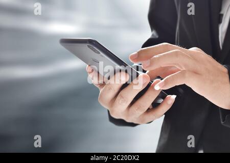 Closeup image of businessman holding and using mobile phone over blur background. Stock Photo