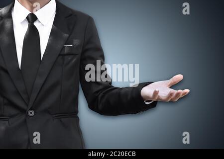 Businessman standing and shows outstretched hand with open palm, copy space. Stock Photo