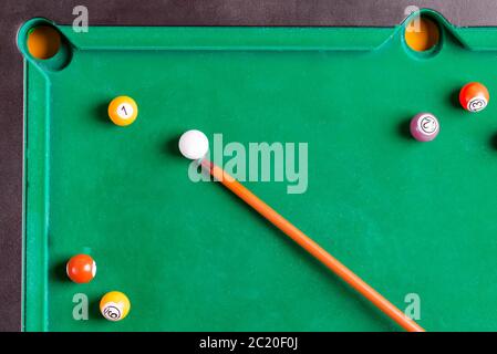 Billiards multicolored balls and cue on billiards green table. Top view. Stock Photo