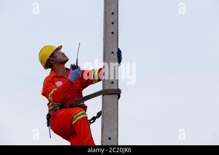 Electricians work on high-voltage electricity poles, along with safety equipment and radio communication. Stock Photo