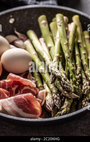 Asparagus eggs bacon and garlic in ceramic pan Stock Photo