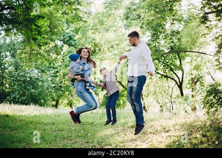 Active and positive family having fun and jumping in park together. Stock Photo