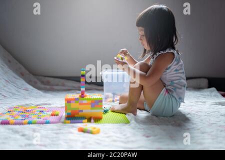 Girl child enjoys playing the lego create a building stay at home Stock Photo