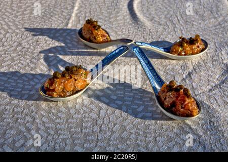 Specialty salmon meat with spices on the table. The meat is decoratively presented in ceramic spoons. Stock Photo