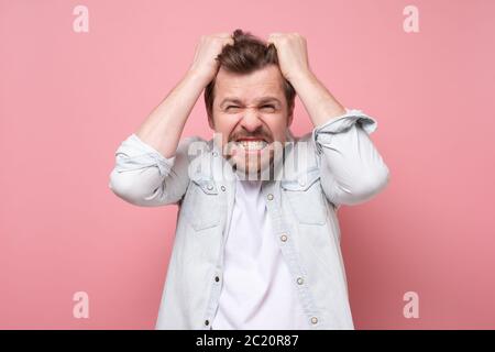 Young man in shock holding hands on head. Stock Photo