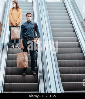 young man in a protective mask standing on an escalator in a shopping center Stock Photo