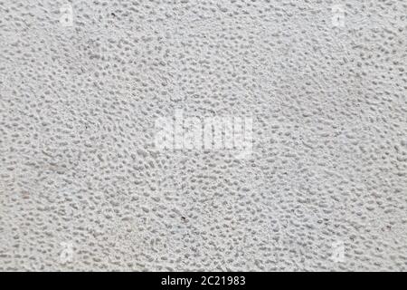 Close-up of a concrete wall with a sanded surface with a texture of gray crumbs on a white background. Pattern or wallpaper of building material. Stock Photo