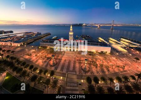 Aerial view of San Francisco Ferry Building and Justin Herman Plaza illuminated at night. Empty during shelter in place due to coronavirus. California Stock Photo