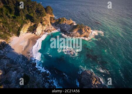 Aerial View of McWay Falls and Cove Beach in BIg Sur, California. McWay Falls is an 80-foot waterfall that flows directly into the Pacific ocean in Ju Stock Photo