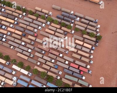 Drone aerial view top shot of row of trucks transporting soybeans in BR 163 road gas station garage on Amazon, Para, Brazil. Concept of transport. Stock Photo