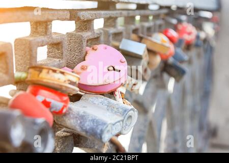 Metal fence - a fence on the city promenade with closed locks of different shapes and colors hung by the newlyweds on the wedding day according to the Stock Photo