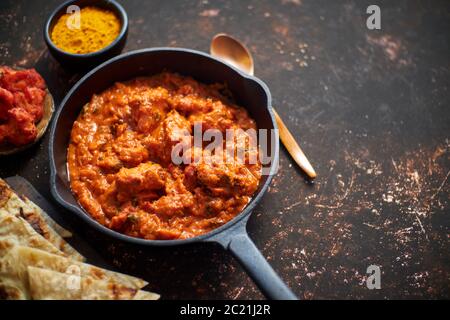 Traditional Indian chicken tikka masala spicy curry meat food in cast iron pan Stock Photo